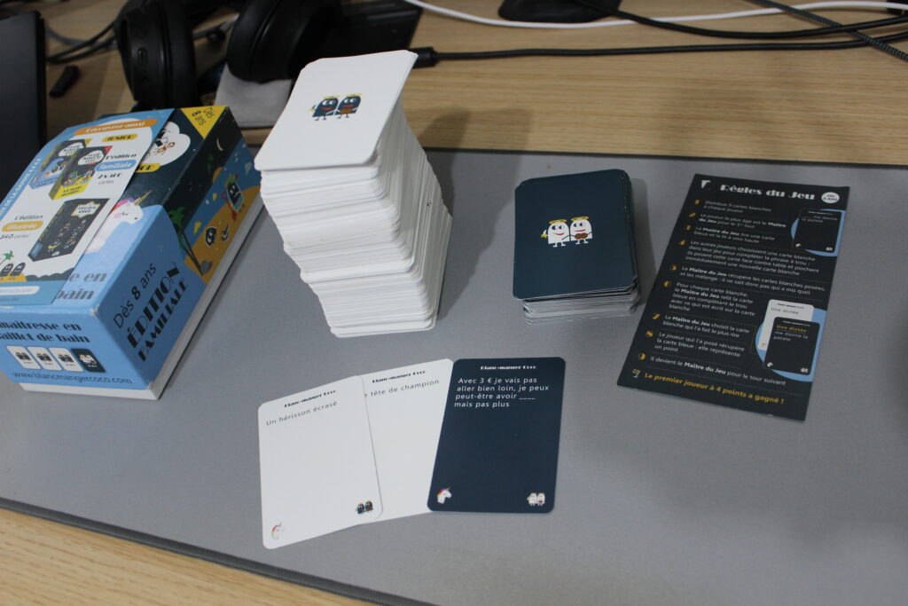 Composition du jeu avec 400 cartes réponse (blanches), 100 cartes questions (bleues) et la notice.